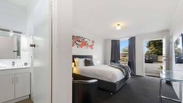 A modern hotel room with a bed, bedside table, and a view of the outside.