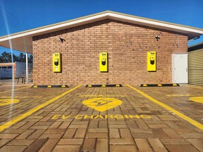An EV charging station with three yellow charging points on a brick building. - Comfort Inn Flinders On Main (Beetaloo Valley)