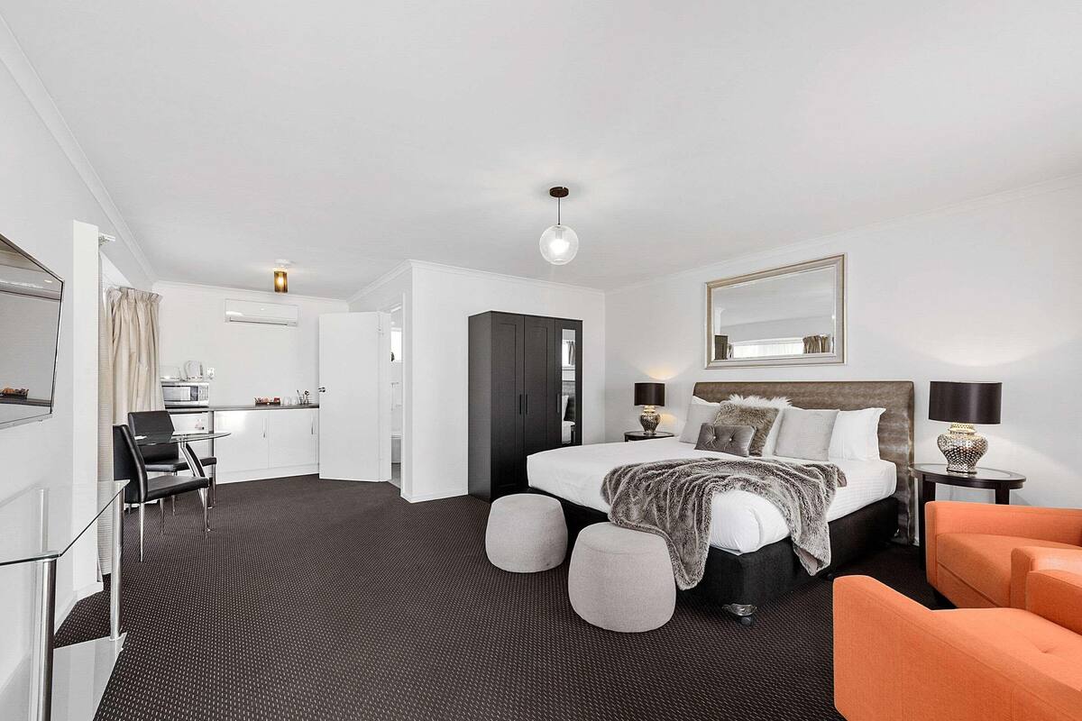 Una habitación de hotel moderna con cama, mesitas de noche, escritorio y silla.