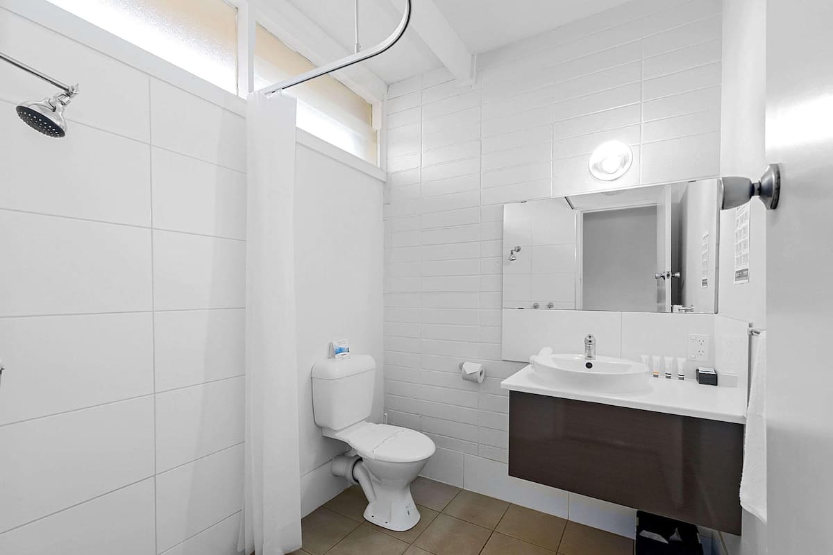 Un baño moderno con inodoro, ducha, lavabo y espejo.
