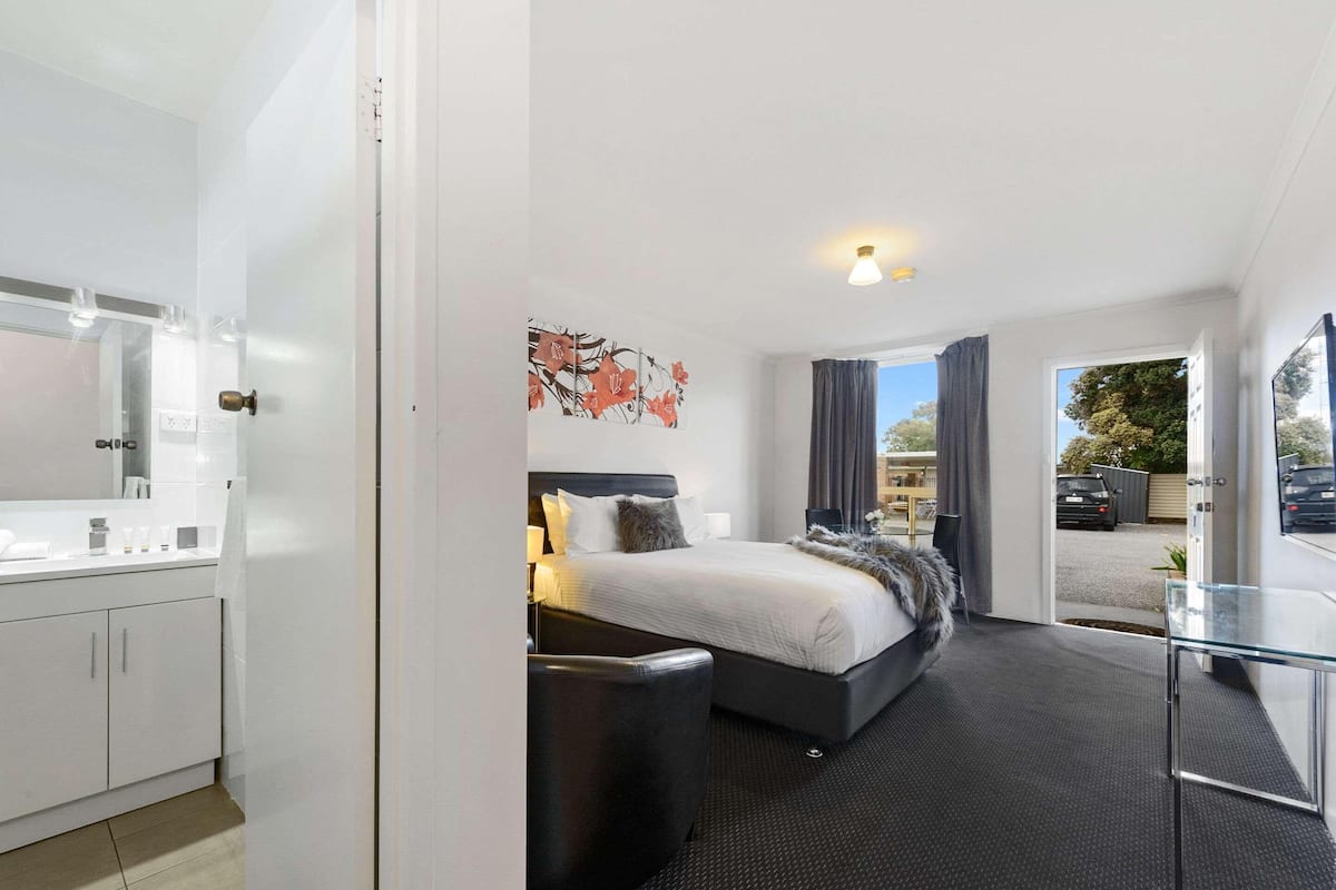 Habitación de hotel moderna con cama, mesita de noche y vistas al exterior.