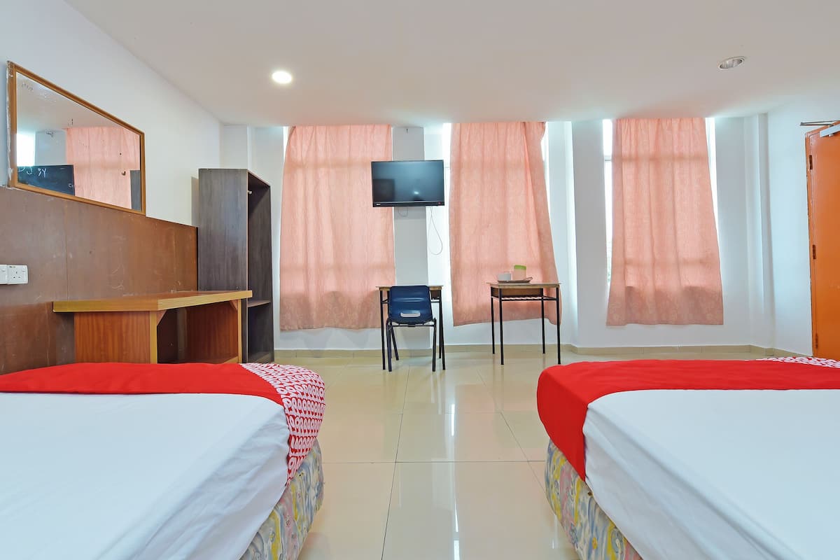 A hotel room with two beds, a desk, a chair, a television, and a wardrobe.