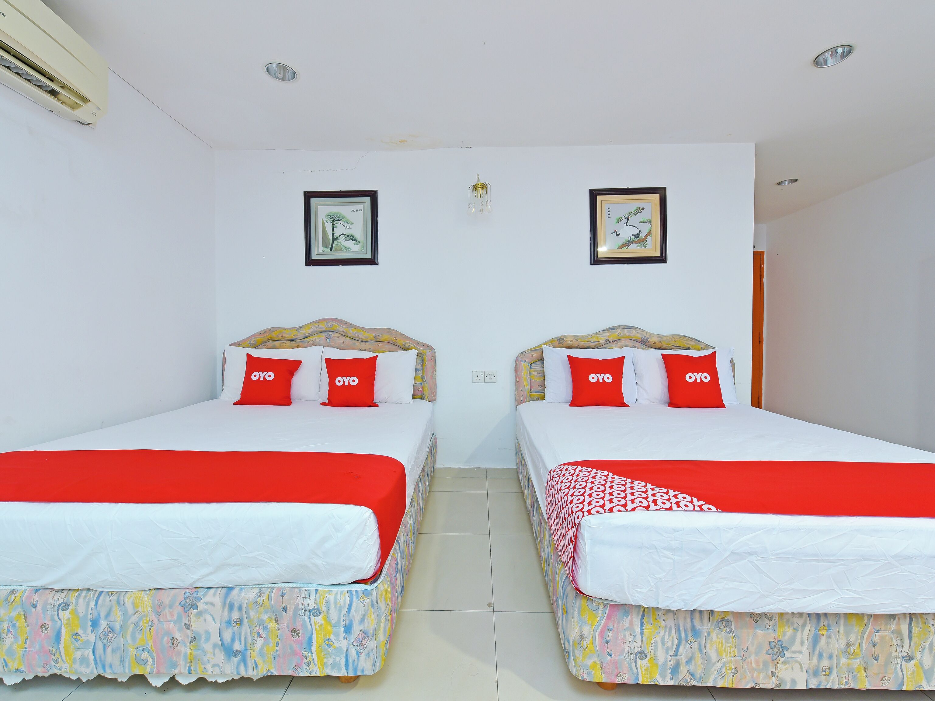 A hotel room with two beds, each with a red and white bedspread and matching pillows.