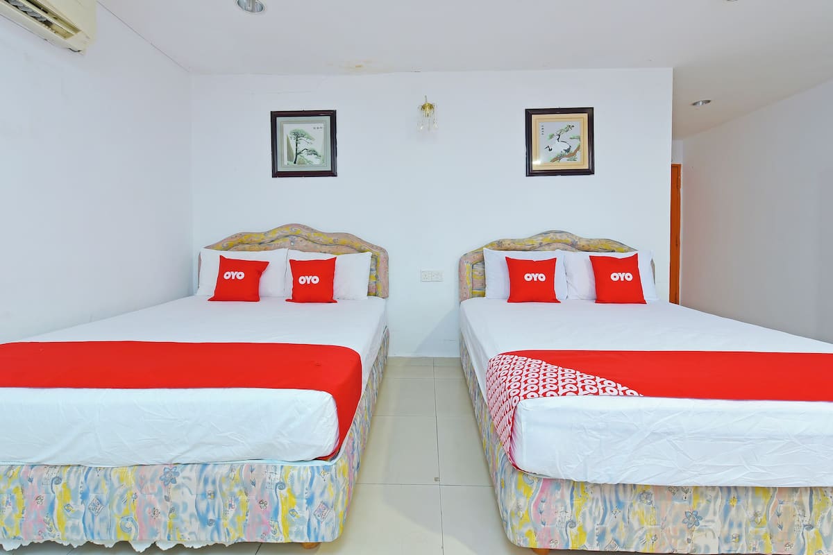 A hotel room with two beds, each with a red and white bedspread and matching pillows.