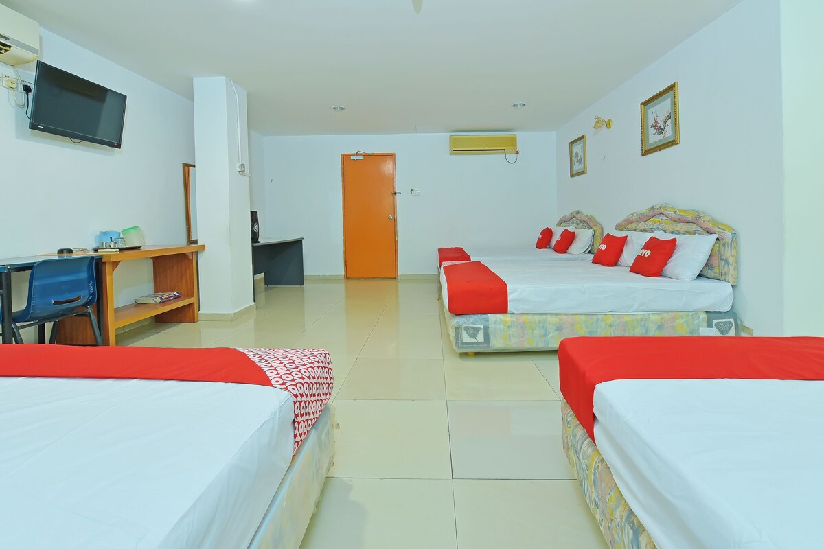 A hotel room with two beds, a desk, a television, and a door.