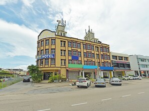 A multi-story hotel with a yellow facade, multiple windows, and a sign indicating it is a hotel. - OYO 90494 Sam Huat Hotel (Pontian)