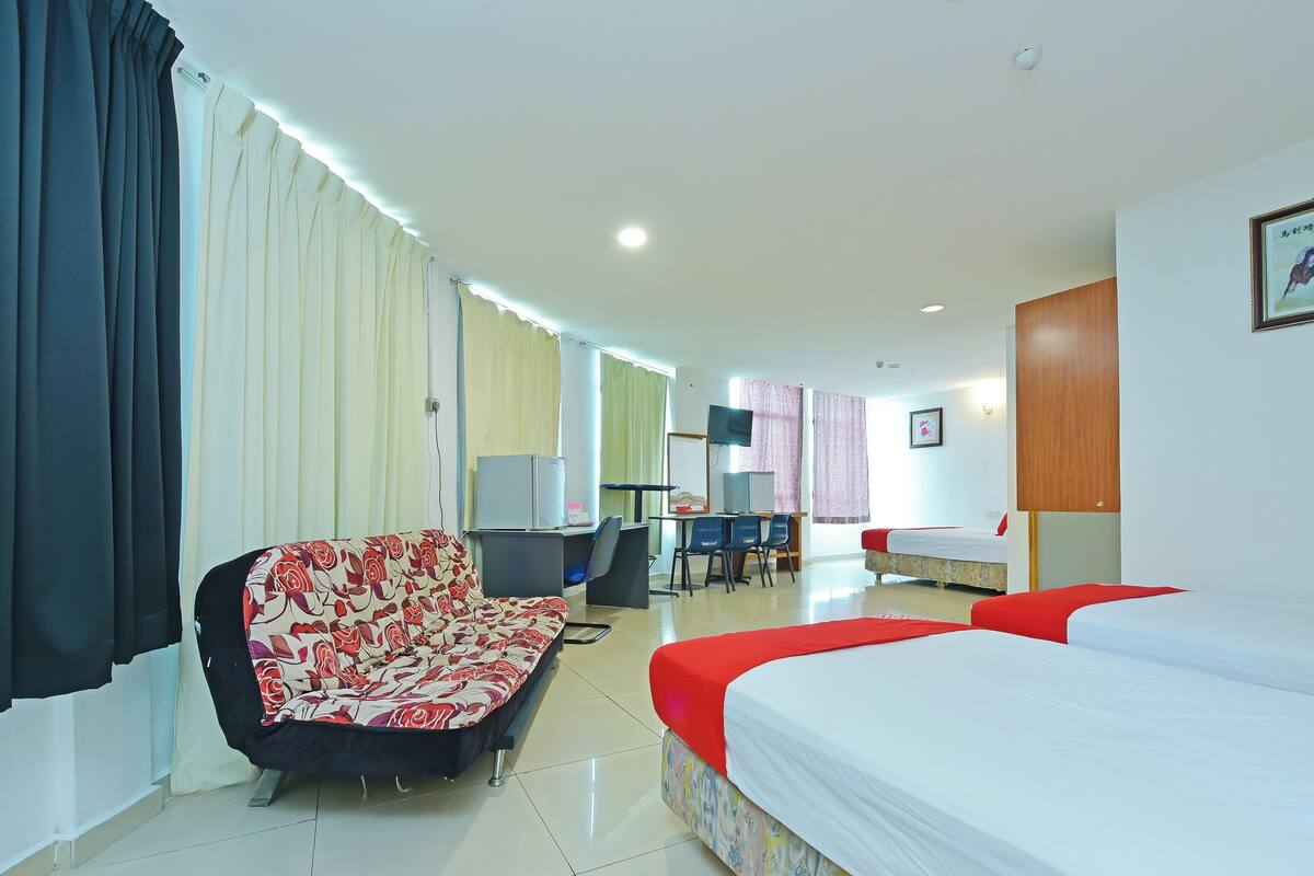 Una habitación de hotel con cama, sofá, escritorio y ordenador, además de televisor.