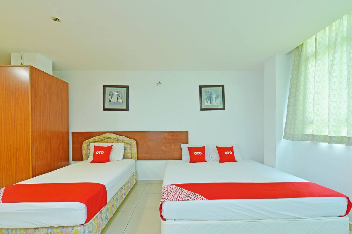 Una habitación de hotel con dos camas, cada una con un edredón rojo y blanco, y un armario de madera.