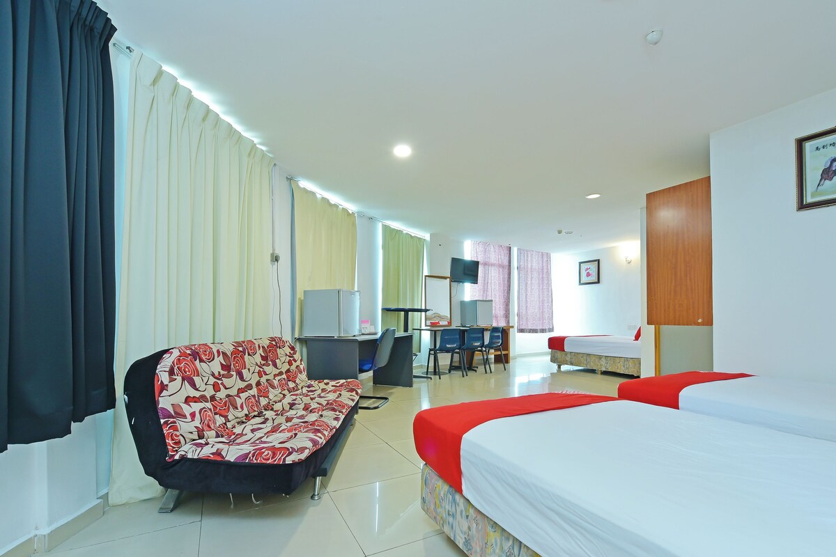 A hotel room with a bed, a sofa, a desk with a computer, and a TV.