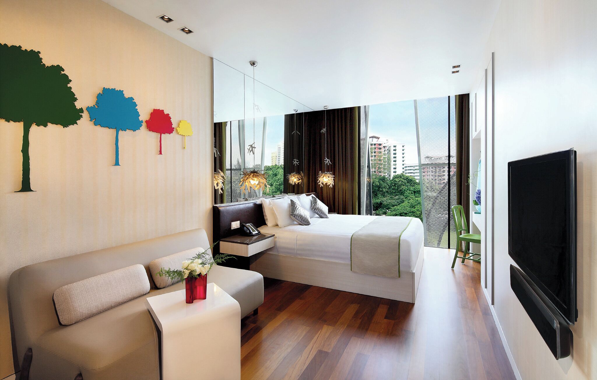 A modern bedroom with a bed, a sofa, a TV, and a city view.