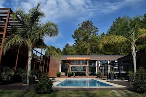 A modern building with a pool, surrounded by palm trees and greenery. - Puerto Dijama (Carmelo)