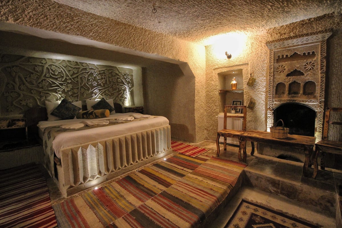 Ein gemütliches Zimmer mit einem Bett, einem Kamin und einem gemusterten Teppich.