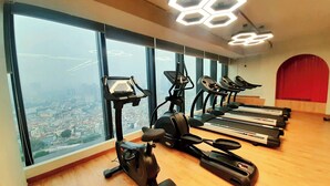 Ein Fitnessstudio mit Trainingsgeräten, großen Fenstern und Blick auf die Stadt.