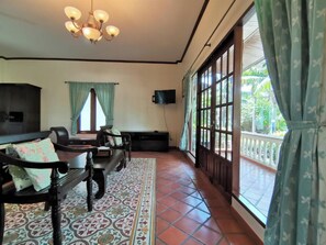 Quarto com uma janela grande, televisão, um banco e piso estampado.