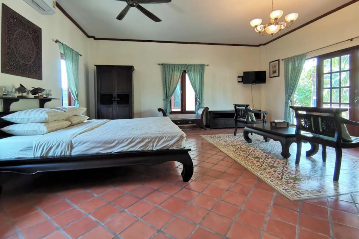 A bedroom with a bed, a ceiling fan, a TV, a desk, and a window with curtains.