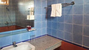 A bathroom with blue tiles, a glass shower enclosure, a sink, and a towel rack.
