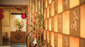 Un interior japonés tradicional con suelo de tatami, un mueble bajo de madera y una pared decorada con caligrafía y obras de arte.