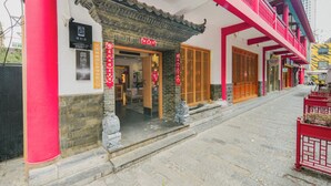 A traditional building with a tiled roof, a wooden door, and a red railing. - Gongxili - Yujian Hotel (Kunming)