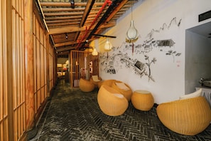 A corridor with wooden paneling, woven seating, and a mural on the wall.