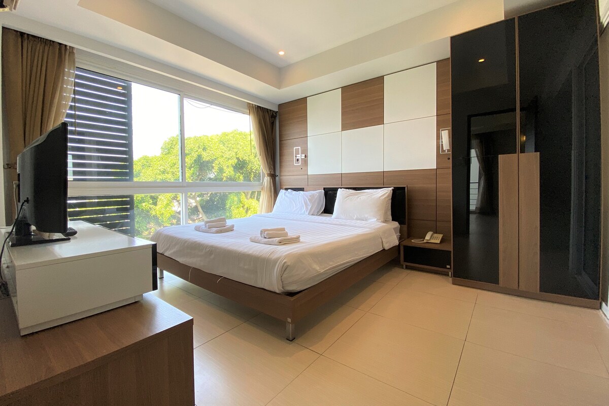 A modern hotel room with a bed, bedside table, and a desk with a computer.