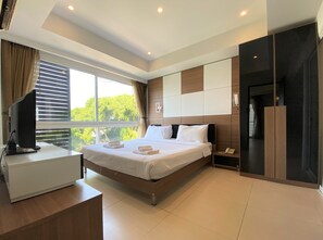 A modern hotel room with a bed, bedside table, and a desk with a computer. - I Am Residence by Zuzu (Patong)