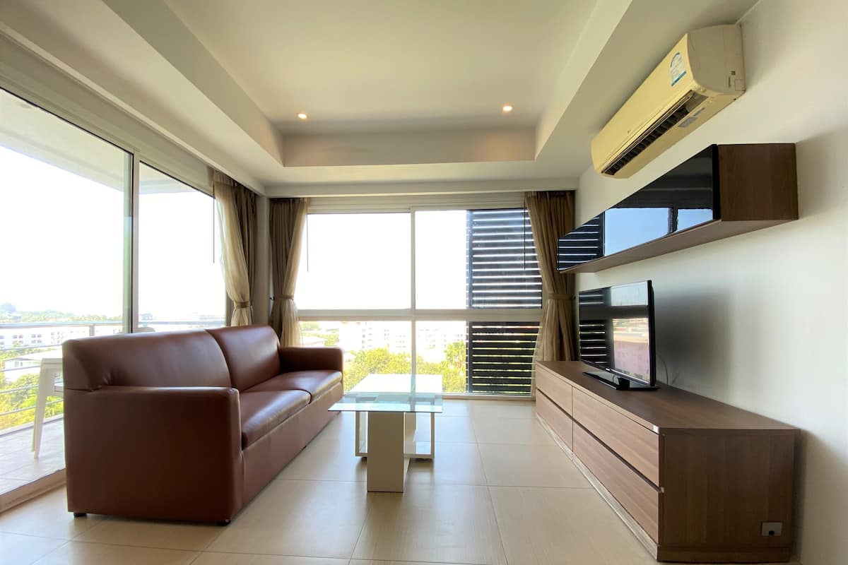 A modern living room with a sofa, TV, and a glass coffee table.