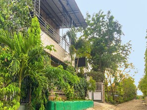 A building with a balcony, surrounded by lush greenery and a gated entrance. - Spot ON 2518 Wilma Hotel Ii Premier (Kupang)