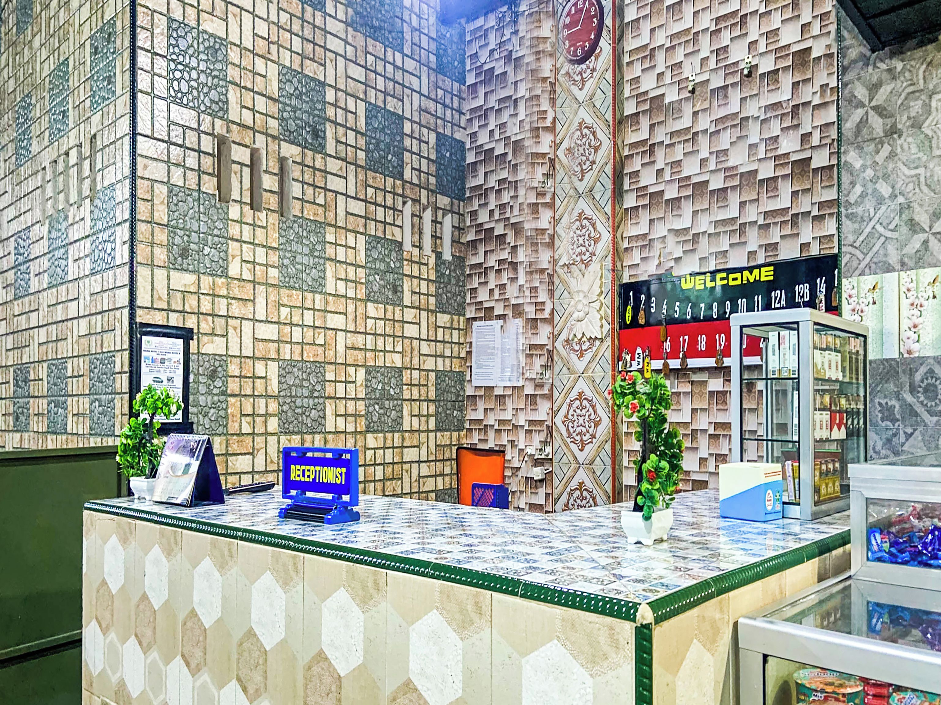A reception area with a patterned wall, a clock, a reception desk, and a welcome sign.
