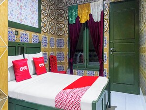 Una cama con ropa de cama roja y blanca, una puerta verde y paredes con diseño.