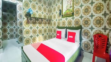A bedroom with a bed, a red chair, and patterned wallpaper.