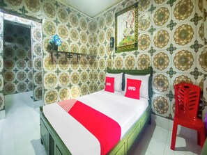 Un dormitorio con cama, una silla roja y papel tapiz estampado.