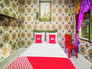 A room with patterned wallpaper, a bed with red and white bedding, and a red chair. - Spot ON 2518 Wilma Hotel Ii Premier (Kupang)