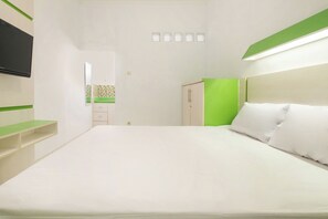 A hotel room with a bed, a television mounted on the wall, a mirror, a wardrobe, and a green accent wall. - Oyo 2392 Kost Safira (Ngaglik)