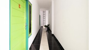 A hallway with a green door, a black and white tiled floor, and a ladder in the distance. - Oyo 2392 Kost Safira (Ngaglik)