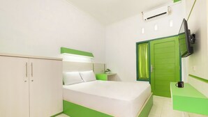 A bedroom with a bed, a wardrobe, a bedside table, a TV, and a green door. - Oyo 2392 Kost Safira (Ngaglik)