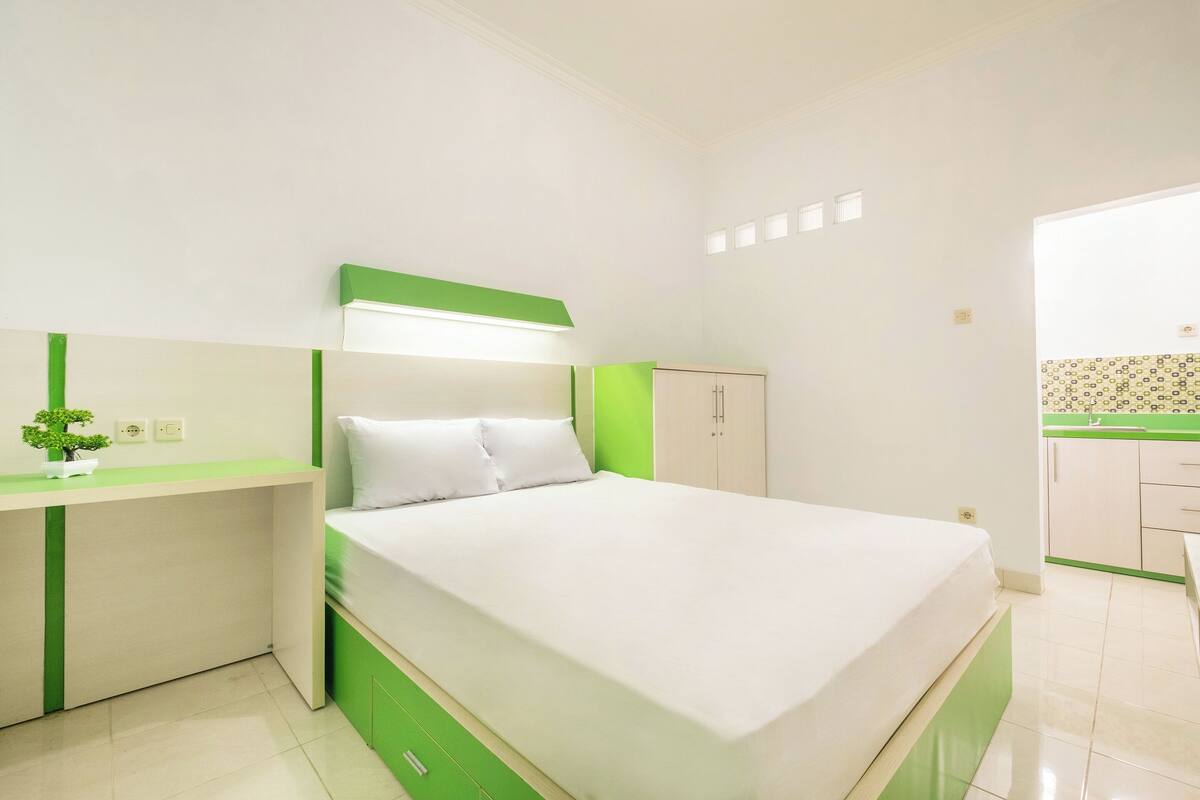 A bedroom with a bed, a desk, and a wardrobe.