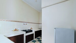 A kitchen with white tiled walls, a checkered floor, and a refrigerator. - Oyo 2392 Kost Safira (Ngaglik)