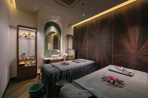 A spa room with a massage table, a sink, a mirror, and a wooden panel wall.