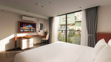Une chambre d’hôtel avec un grand lit, un bureau avec une chaise, une télévision et une vue sur l’extérieur.