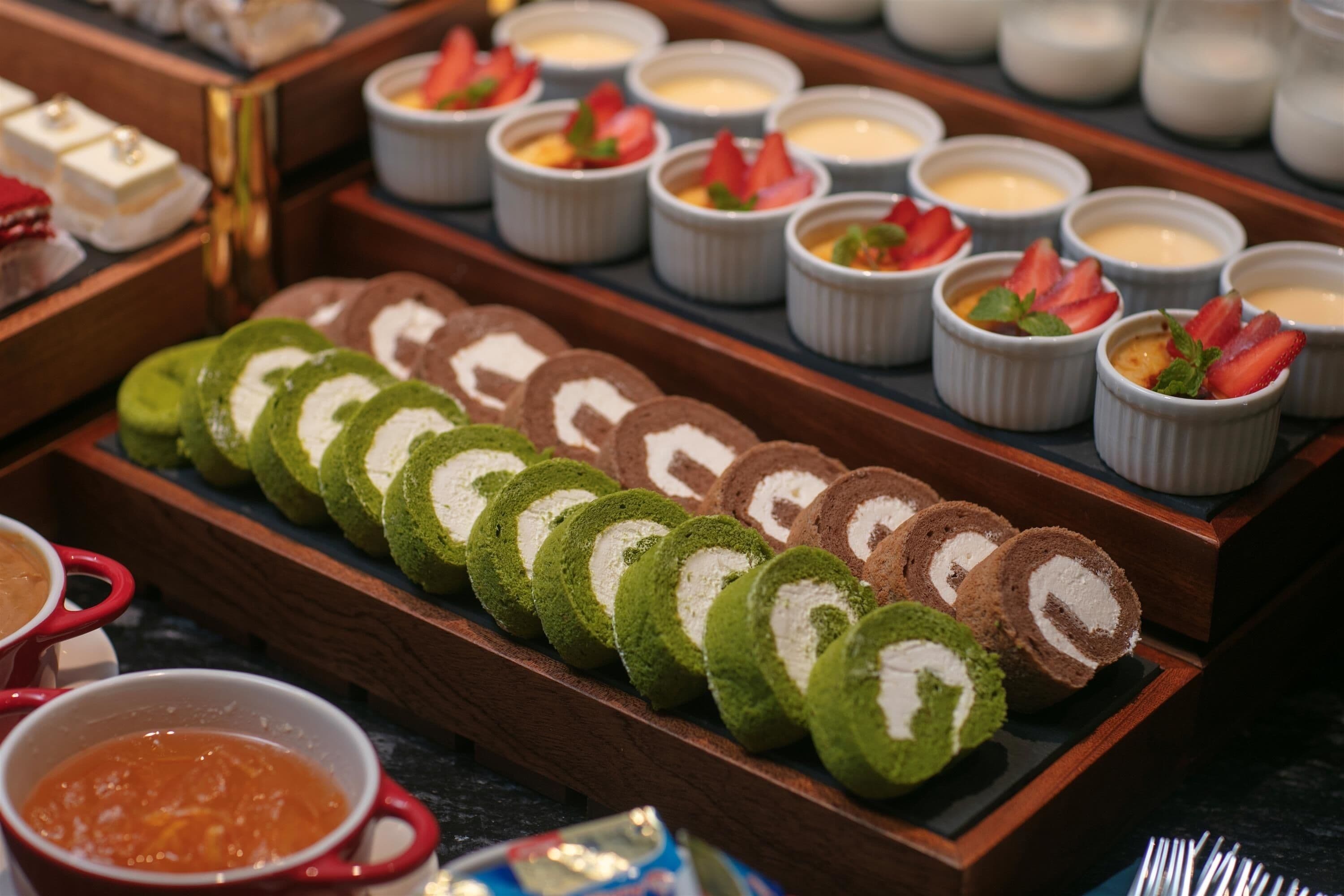 Una mesa de postres con diversos dulces y pequeños recipientes de crema.