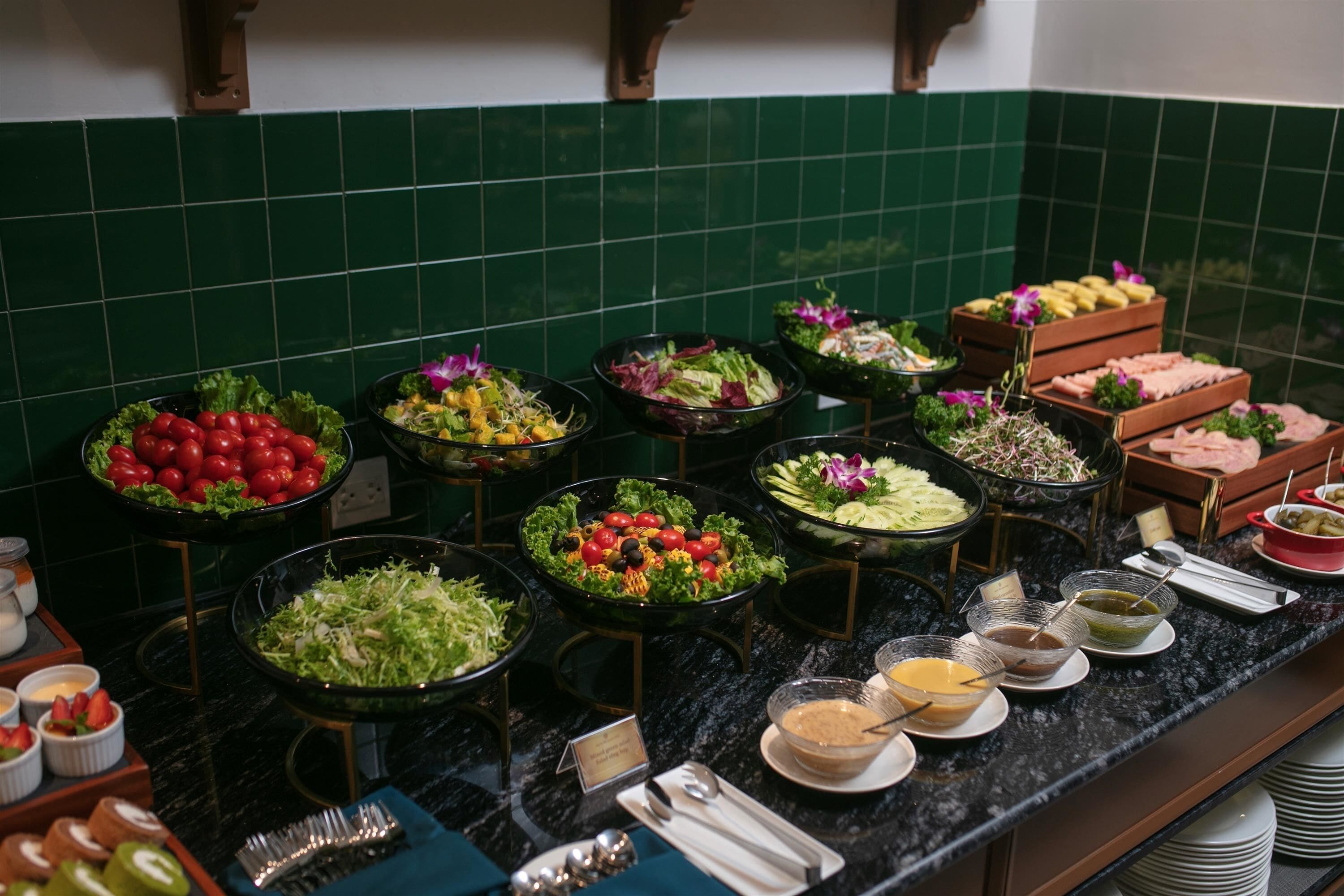 A buffet with various food options, including salads, fruits, and meats, arranged on a marble countertop.