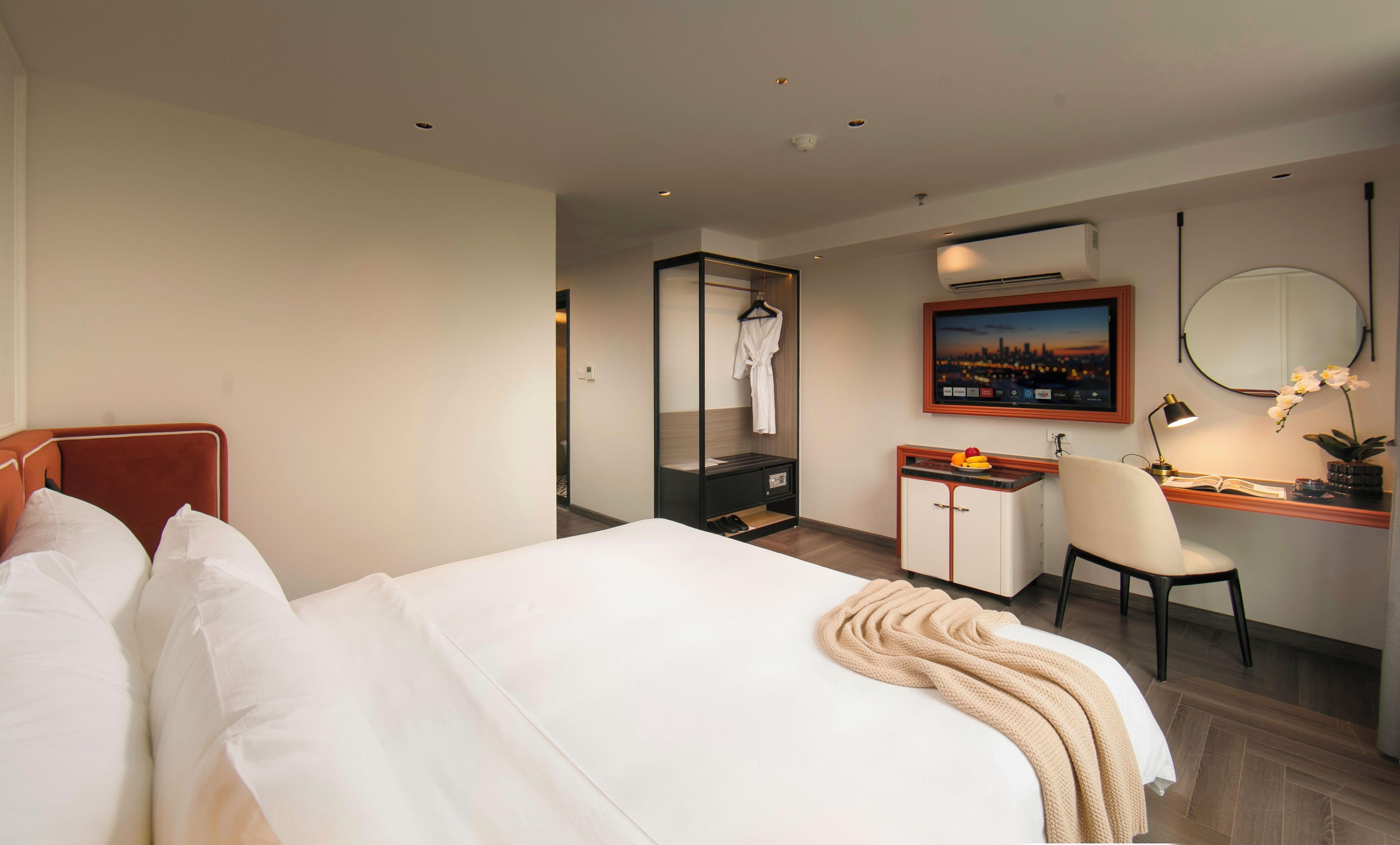 Ein Hotelzimmer mit einem Bett, einem Schreibtisch, einem Stuhl, einem Spiegel und einer Klimaanlage.