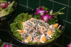 A salad bowl with green beans, eggs, and other ingredients, garnished with flowers.