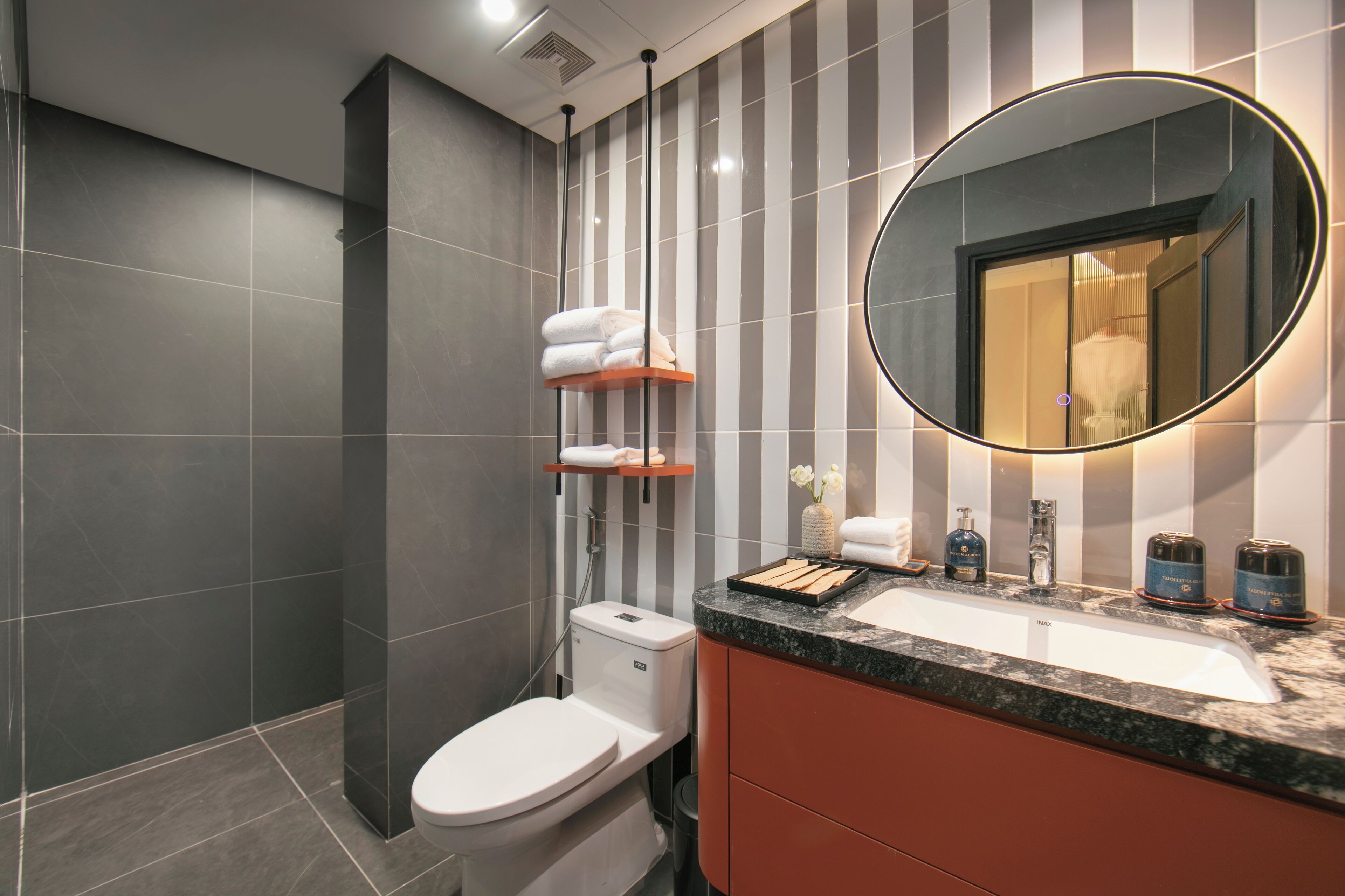 Ein modernes Badezimmer mit Toilette, Waschbecken mit Spiegel und Handtuchhalter.
