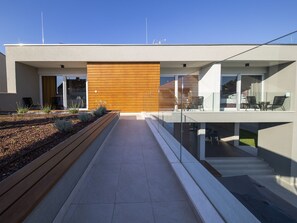 Un edificio moderno con techo plano, pared de paneles de madera y balcón de vidrio.