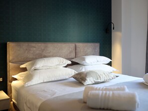 Ein ordentlich bezogenes Bett mit vielen Kissen und einer gefalteten Decke in einem Hotelzimmer.
