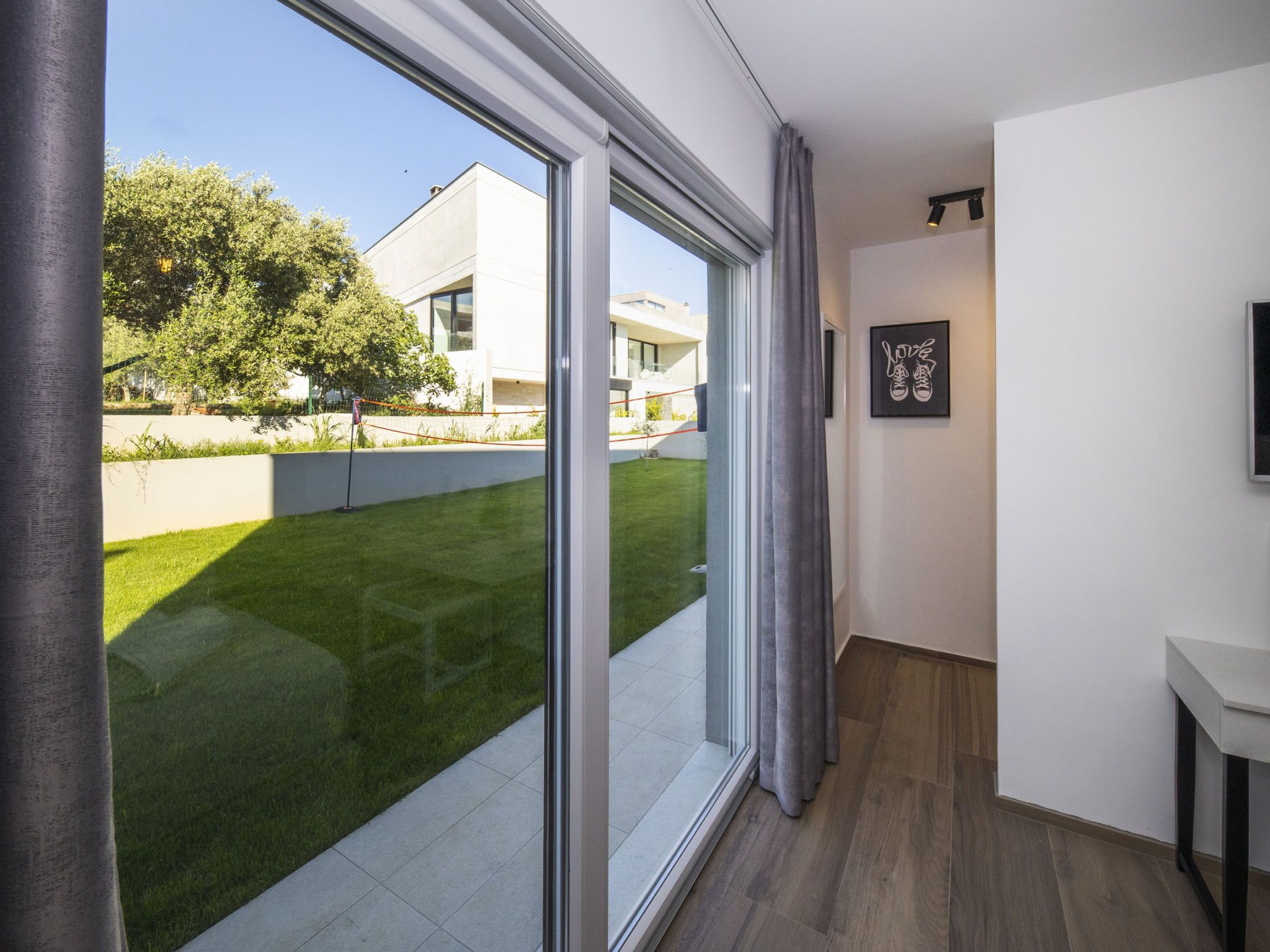 Un intérieur moderne avec une grande porte-fenêtre coulissante donnant sur un espace extérieur bien aménagé.