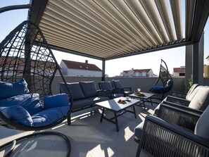 Eine Außenpatio mit Sitzgelegenheiten, darunter ein Hängesessel, Sofas und Tische.