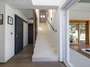 Una escalera conduce a un segundo piso, con barandilla de madera, una puerta en la parte inferior y una pared con cuadros enmarcados.