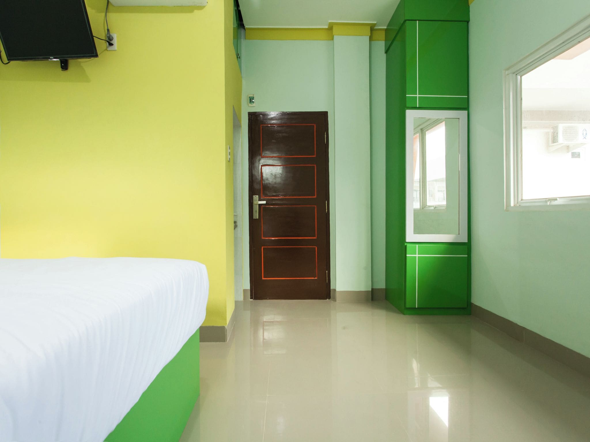 A hotel room with a bed, a door, and a window.